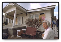 woman in front of damaged house 